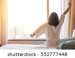 Easy lifestyle Asian woman waking up from good sleep in weekend morning taking some rest, relaxing in comfort bedroom at hotel window, having happy lazy day enjoying work-life quality balance concept