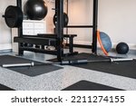 Small photo of Indoor garage gym setup with home exercise and fitness equipment. Lifting rack, bench and bar ready for use. Home gym with natural light.