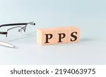 Small photo of wooden cubes with the word PPS - Pay Per Sale on a financial background with chart, calculator, pen and glasses, business concept.