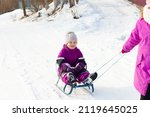 Small photo of Two funny little girls having fun with a sleight in beautiful winter park. Cute children playing in a snow. Winter activities for kids.