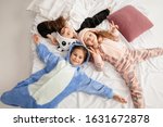 Children in soft warm pajamas colored bright playing at home. Little girls having fun, party, laughting, playing together, look stylish and happy. Concept of childhood, leisure activity, happiness.
