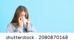 Small photo of Flu. Portrait of young beautiful girl in warm winter clothes sneezes, snots isolated on navy color background in neon. Concept of emotions, facial expression, youth, aspiration. Copy space for ad