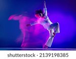 Small photo of Dynamic portrait of beautiful girl, hip-hop dancer in white outfit dancing hip hop isolated on blue background in pink neon light. Youth culture, hip-hop, movement, style and fashion, action.