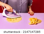Small photo of Pop art photography. Creative portrait of girl ironing pancakes on lilac color tablecloth. Vintage, retro 80s, 70s style. Complementary colors, Copy space for ad, text