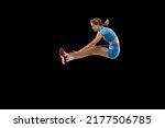 Side view. Young sportive girl, long jumper in sports blue uniform performs triple jump isolated on black background. Concept of sport, action, motion, speed, healthy lifestyle. Copy space for ad
