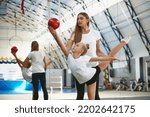 Sport training with coach. Preparing for sport competition. Beginner gymnastics athletes doing exercises with gymnastics equipment at sports gym, indoors. Concept of achievements, studying, goals