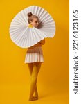 Small photo of Mystery, intrigue. Young pretty girl in giant jabot collar or neckwear and yellow tights isolated over yellow background. Contemporary art