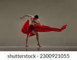 Small photo of Toreador. Artistic performance with young handsome man dancing with red fabric against grey studio background. Concept of art, classical dance, inspiration, creativity, fashion, beauty, choreography