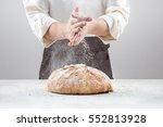 The male hands in flour and rustic organic loaf of bread