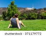 Girl sitting at in the Lake Hollywood Park and the Hollywood sign in the background in Los Angeles