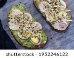 Appetising healthy breakfast. Two slices of avocado toast on a homemade sourdough brown bread with sliced eggs, mungo bean sprouts, fresh pepper and chilli flakes