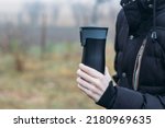 Small photo of In late autumn, men's hands are warming themselves on a black toggle switch with a hot drink. Environmentally friendly use of reusable glasses, mugs. Rejection of plastic.
