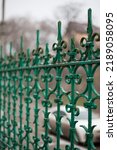Small photo of green wrought-iron mangy church fence on a blurry background