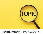 The word TOPIC is written on a magnifying glass on a yellow background.