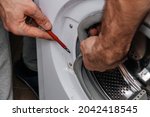 Handyman repairing a washing machine. The hands of a man repair a washing machine. Close-up