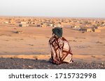 Arabian woman sit looking to her town in the middle of the desert at Tindouf, Argel