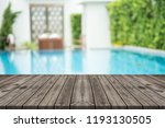 Empty wooden table in front with blurred background of swimming pool 
