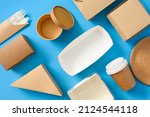 A lot of paper disposable tableware is stacked evenly on a blue background. Use of eco-friendly tableware food delivery. flat lay.