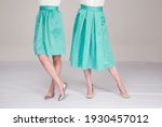Two girls in mint skirts with their backs on a light background.