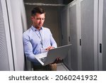 Small photo of Colocation center employee entering data into laptop