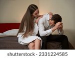 Small photo of Caring girlfriend consoling despondent boyfriend in hotel room
