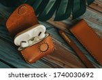 Apple wireless earphone in leather case on wooden background