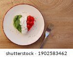 Heart shaped Italian Caprese Salad arranged by Italian basil,buffalo mozzarella and tomatoes look like Italian Flag on plate with wooden table background.Love Italian food concept for Valentine day 
