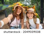 Cute child feeling happy and smiles with her mother while playing with parrot bird. Asian family portrait people. Environment human and nature concept, Smiling girl playing with pet, Sun Conure.