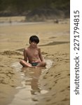 Small photo of portrait of a child sitting on a beach water bringer