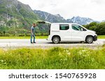Young man open the trunk of his hired car to get some stuff on mountains background