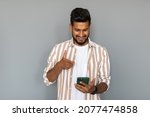 Small photo of Portrait of indian man having phone in hands, checking email, using 3G, wi-fi internet, searching contact, isolated on grey background