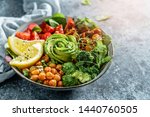 Buddha bowl salad with baked sweet potatoes, chickpeas, broccoli, tomatoes, greens, avocado, pea sprouts on light blue background with napkin. Healthy vegan food, clean eating, dieting, close up
