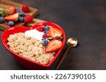 Oatmeal porridge with berry and yogurt in red bowl in the heart shape, top view. Oat flakes healthy breakfast meal. Clean eating, dieting, healthy food. Copy space