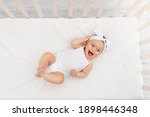 happy baby is lying in a crib in the children's room on a white bed