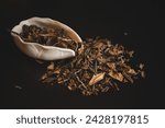 Small photo of A white bowl filled with tobacco leaves sits atop a mound of natural material, surrounded by terrestrial animals and wildlife in the darkness of the soil