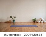 Yoga mat lying on wood floor in a yoga studio. Yoga studio decorated with sport's equipment and tropical plants.