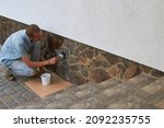 Small photo of varnish the stone on the house,stone with foundation man applies varnish with a brush