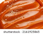 Liquid salted caramel syrup. Background of salted caramel paste. Texture Close up, top view. Sea salt pieces on caramel.