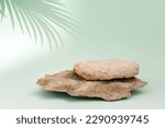 Stone podium for cosmetic product presentation. Abstract minimal backdrop. One rock form, palm leaf shadow, sunlight. Scene to show. Showcase, display case. 3D Front View. Trendy summer green color.