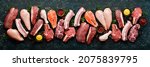 Small photo of Set of various classic, alternative raw meat, veal beef steaks, pork, chicken fillet, fish, salmon steak. Top view. On a black stone background.