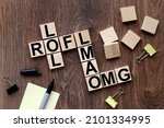 Small photo of LOL Laugh out loud, LMAO, ROFL, OMG, text message abbreviation on wooden cubes in the form of a crossword puzzle. Internet slang.