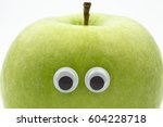 green apple with googly eyes on white background - portrait