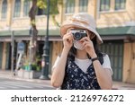 Traveler, travel asian young woman or girl use camera take photo, old town street, city tourism on happy sunny day. Backpacker tourist, holiday trip, summer or vacation, hobby concept.