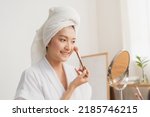 Happy beauty blogger concept, cute asian young woman, girl smile, make up face by applying brush blush powder on her cheek, looking at the mirror. People look with natural fashion style.