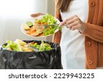 Compost from leftover food, asian young housekeeper woman hand holding cutting board use fork scraping waste, rotten vegetable throwing away into garbage, trash or bin. Environmentally responsible.