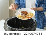 Small photo of Compost from leftover food, refuse asian young housekeeper woman, girl hand using fork scraping waste from dish, throwing away putting into garbage, trash or bin. Environmentally responsible, ecology.