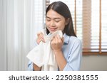 Small photo of Feel softness, smiling asian young woman, girl touching fluffy towel cotton, smelling fresh clean clothes on table after washing, laundry, dry. Household working at home. Laundry and maid.