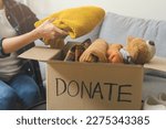 Small photo of Recycling, Donation for poor, asian young woman, girl sitting pack object at home, putting on stuff into donate box with second hand clothes, charity helping and needy people. Reuse recycle, moving.