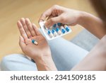 Sick ill asian young woman, girl hand taking tablet pill capsule out from blister pack, painkiller medicine from stomach pain, head ache, pain for treatment, take drug or vitamin at home, health care.