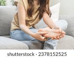 Small photo of Foot pain concept, close up hand of young woman rubbing, massaging sore feet area of pain, girl suffering on sofa, couch at home. Discomfort painful feet ache from walking for long. Physical injury.